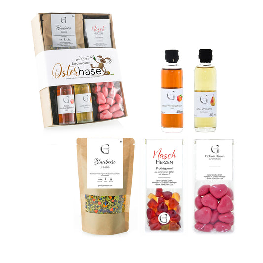 Hochwertiges Oster-Geschenkset von Genial Genießen mit Pistazien-Sahnelikör, Eierlikör, Mango Crema, Tee und Schokoladenkugeln, stilvoll arrangiert als festliches Geschenk zum Osterfest.